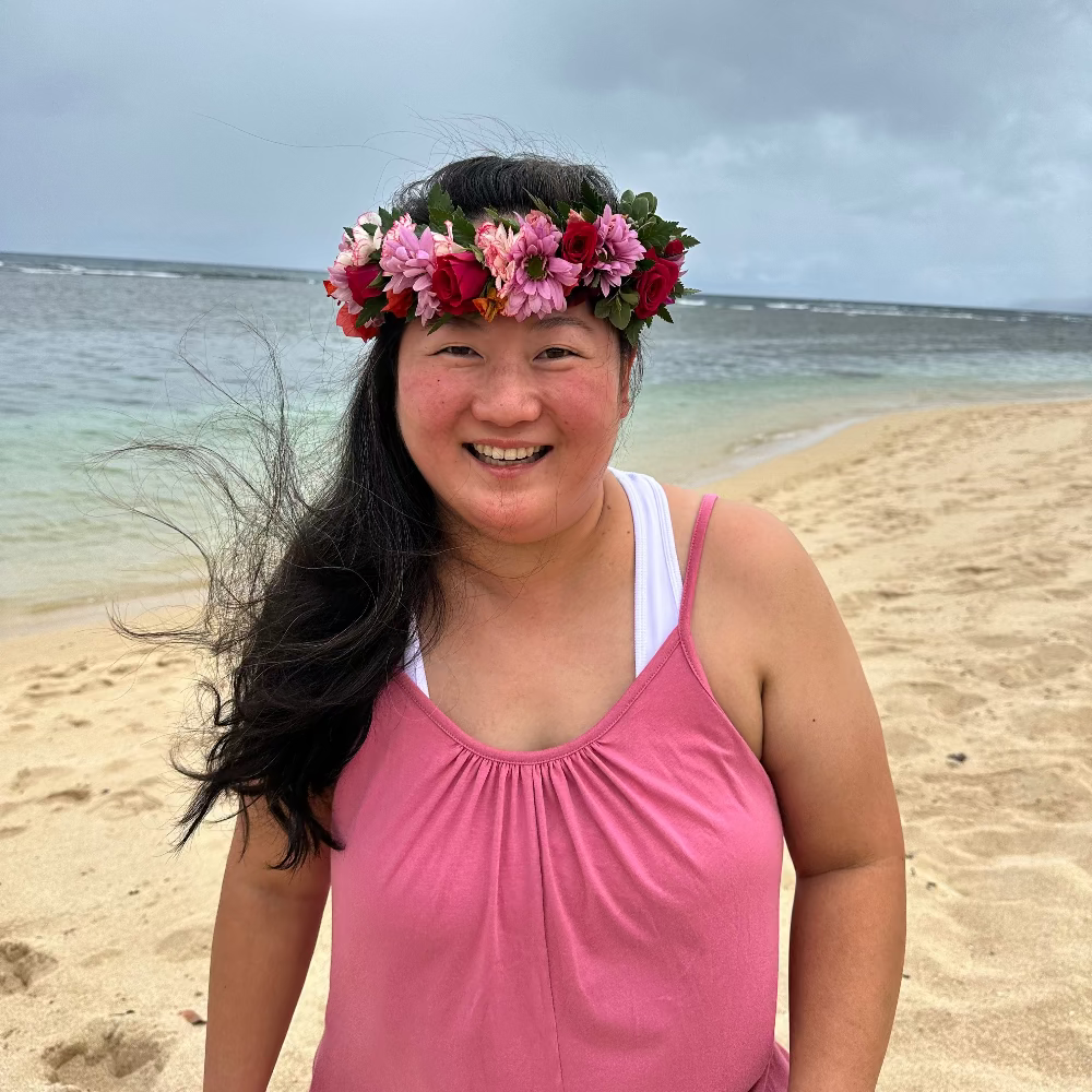 Woman with a floral crown on a beach with ocean and sky in the background