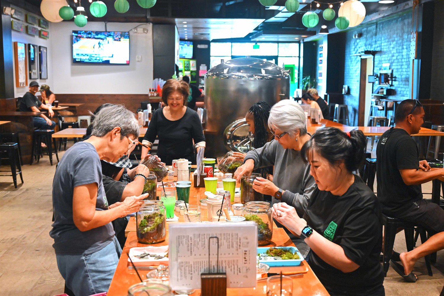 Group of people sitting around a table in a casual dining setting with drinks and food.
