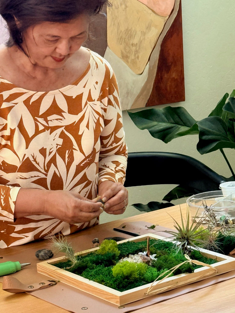Person working on a small garden or terrarium project at a table.