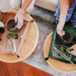 Two people working with plants on round tables, wearing gloves.