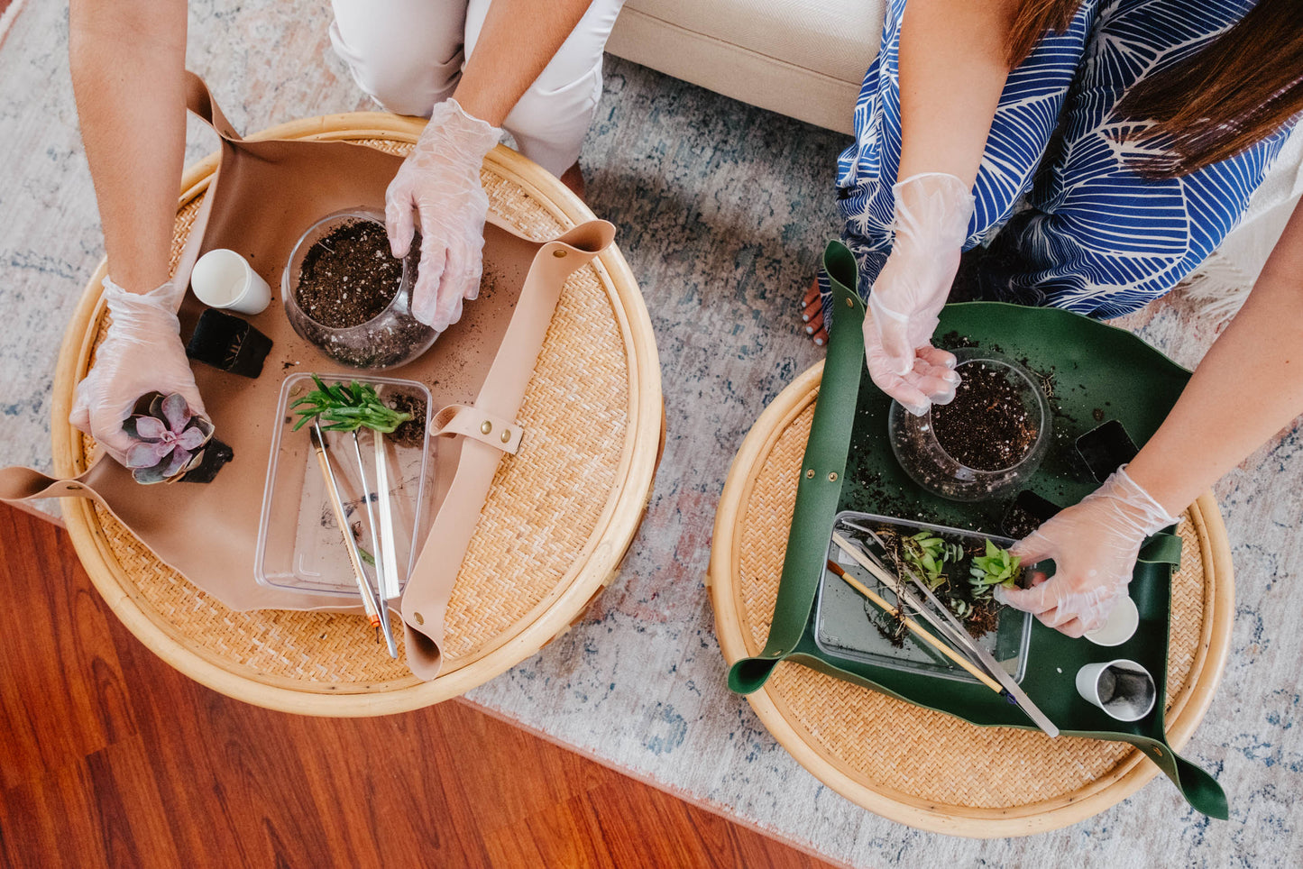 Two people working with plants on round tables, wearing gloves.