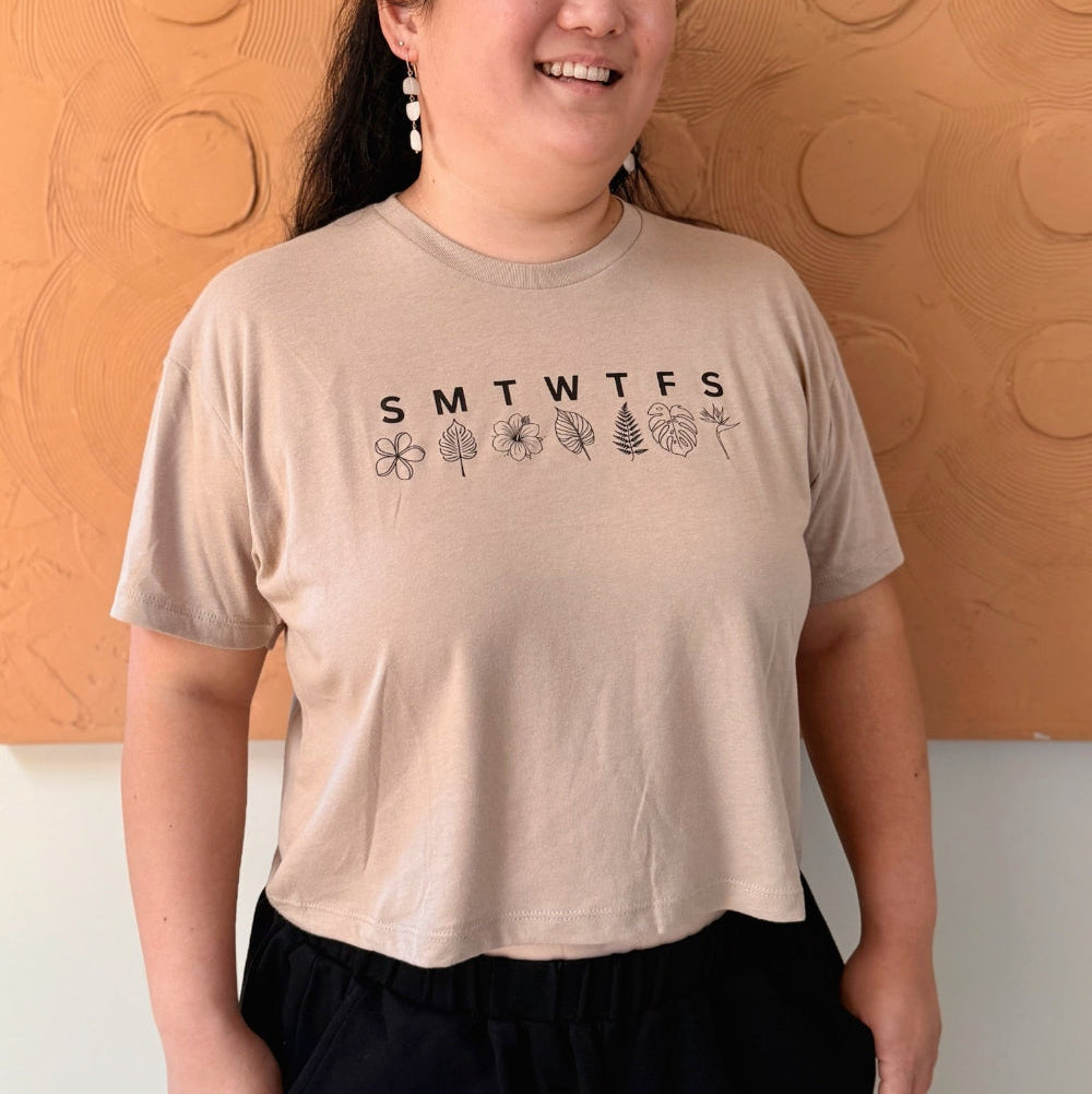 Person wearing a beige t-shirt with a printed design against an orange wall.