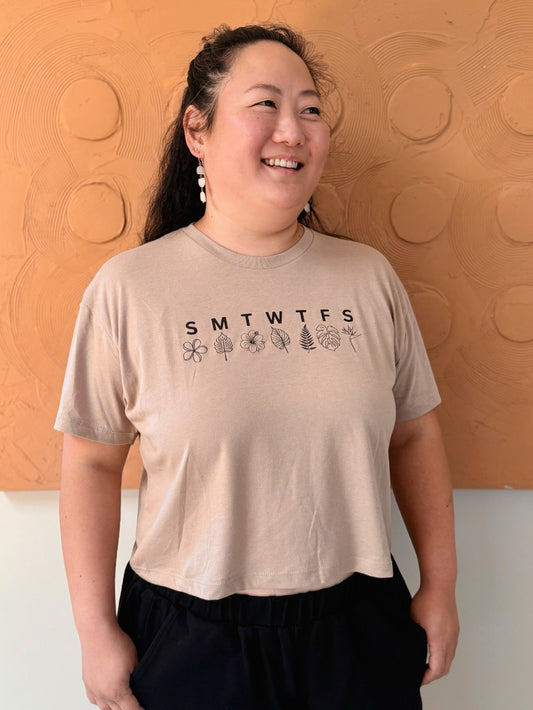 Person wearing a beige t-shirt with a printed design against an orange wall.