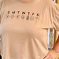 Beige t-shirt with 'SMTWTFSS' and leaf designs worn by a person.