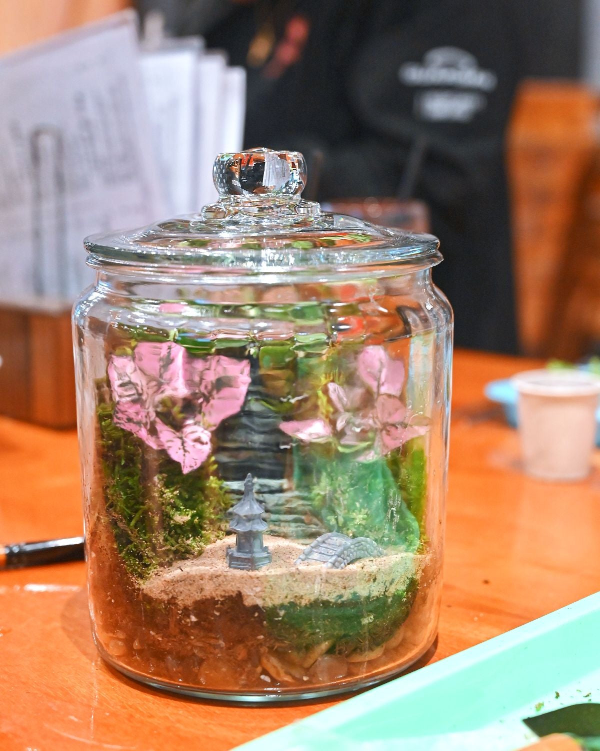 Decorative jar with plants and a small landscape on a table