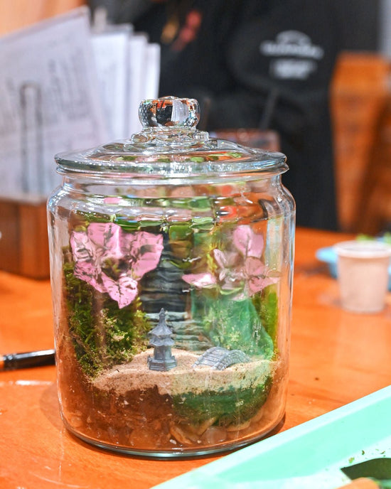 Decorative jar with plants and a small landscape on a table
