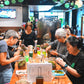 Group of people sitting around a table in a casual dining setting with drinks and food.