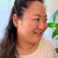 Woman with a ponytail wearing a white shirt with text, indoors with a blurred background