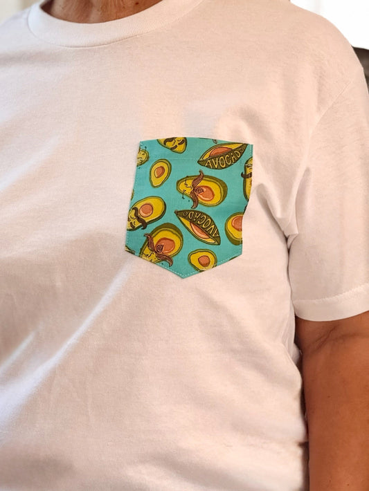 White t-shirt with a colorful avocado pattern pocket on a plain background